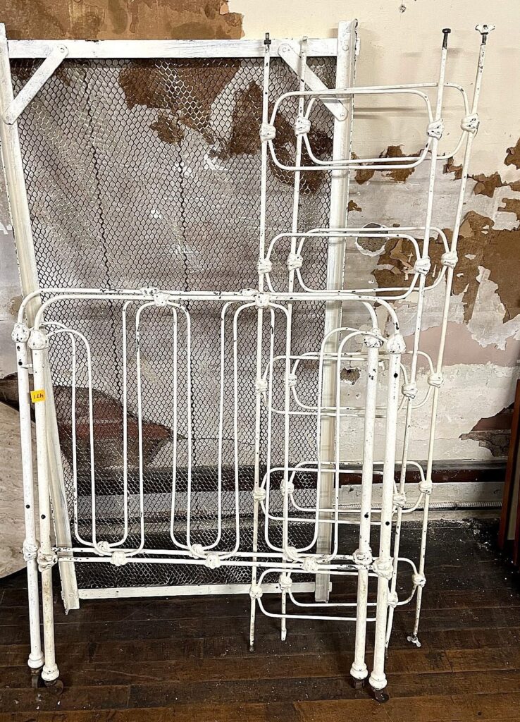 Antique white iron baby crib with wire mesh sides and original painted finish